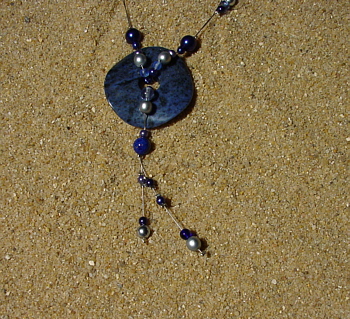 Wachs- und Glasperlen in verschiedenen blaut&ouml;nen und silberfarben, ein 4 cm gro&szlig;er Sodalith-Donut, 44 cm.